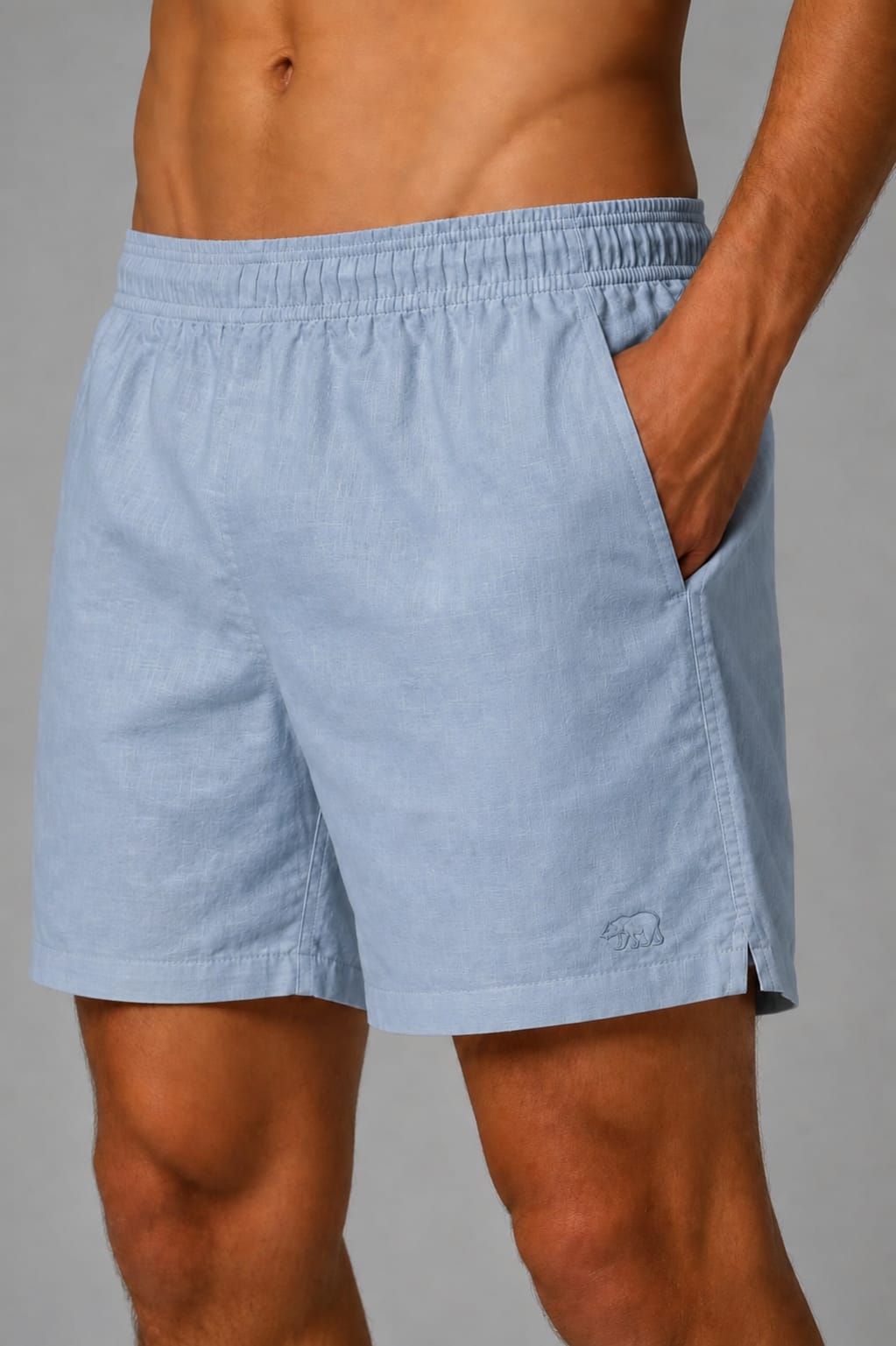 Detalhe de short de linho azul-claro Bransk com bolso lateral e urso bordado